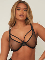 Woman wearing a black strappy bra against a plain background