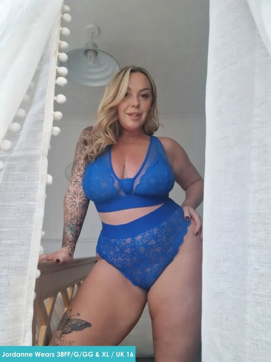 Woman wearing a blue lace lingerie set in a softly lit room.